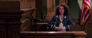 Movie still from “Legally Blonde” (2001), directed by Robert Luketic – A woman sitting at a table in front of a microphone; Medium shot, High angle