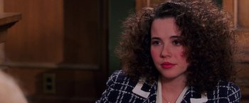 A young woman with curly brown hair wearing a black and white jacket