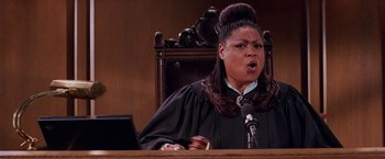 Movie still from “Legally Blonde” (2001), directed by Robert Luketic – A woman in a court robe is holding a gavel; Close Up shot, Low angle