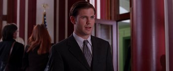 Movie still from “Legally Blonde” (2001), directed by Robert Luketic – A man in a suit and tie standing in front of a window; Close Up shot, Over the shoulder angle