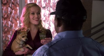 Movie still from “Legally Blonde 2: Red, White & Blonde” (2003), directed by Charles Herman-Wurmfeld – A woman holding a small dog in her hand and smiling; Medium shot, Over the shoulder angle