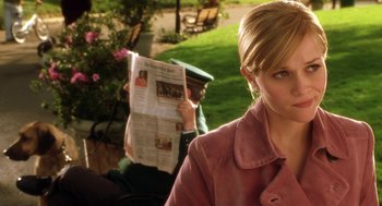 Movie still from “Legally Blonde 2: Red, White & Blonde” (2003), directed by Charles Herman-Wurmfeld – A woman in a pink jacket is reading a newspaper; Close Up shot, Over the shoulder angle