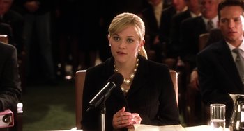 Movie still from “Legally Blonde 2: Red, White & Blonde” (2003), directed by Charles Herman-Wurmfeld – A woman in a black jacket is speaking into a microphone; Medium shot, Low angle