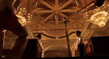 Movie still from “Legally Blonde 2: Red, White & Blonde” (2003), directed by Charles Herman-Wurmfeld – Two men standing in front of a microphone in front of an ornate ceiling; Extreme Wide shot, Low angle