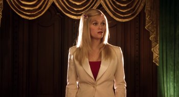 Movie still from “Legally Blonde 2: Red, White & Blonde” (2003), directed by Charles Herman-Wurmfeld – A woman in a white jacket standing in front of a curtain; Medium shot, Low angle