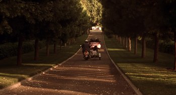 Movie still from “Legally Blonde 2: Red, White & Blonde” (2003), directed by Charles Herman-Wurmfeld – A person riding a motorcycle down a street at night; Extreme Wide shot, High angle
