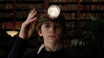 Movie still from “A Series of Unfortunate Events” (2004), directed by Brad Silberling – A young boy wearing a hat with a light on top of his head; Close Up shot, High angle