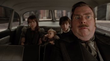 Movie still from “A Series of Unfortunate Events” (2004), directed by Brad Silberling – A group of people sitting in the back of a car; Close Up shot, Over the shoulder angle