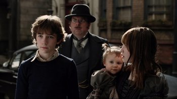 Movie still from “A Series of Unfortunate Events” (2004), directed by Brad Silberling – A group of people standing next to each other on a street; Close Up shot, Over the shoulder angle