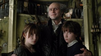 Movie still from “A Series of Unfortunate Events” (2004), directed by Brad Silberling – A man and two children pose for a picture; Medium shot, Low angle