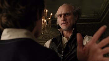 Movie still from “A Series of Unfortunate Events” (2004), directed by Brad Silberling – A man in a black vest is talking to another man in a black vest; Close Up shot, Over the shoulder angle
