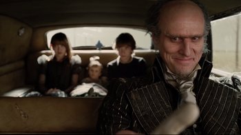Movie still from “A Series of Unfortunate Events” (2004), directed by Brad Silberling – A group of people sitting in the back of a car; Close Up shot, Over the shoulder angle