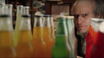 Movie still from “A Series of Unfortunate Events” (2004), directed by Brad Silberling – A man sitting in front of a row of bottles; Close Up shot, Over the shoulder angle