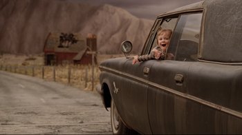Movie still from “A Series of Unfortunate Events” (2004), directed by Brad Silberling – A young child sitting in the drivers seat of an old car; Medium shot, Over the shoulder angle