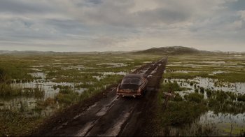 An old car driving down a dirt road