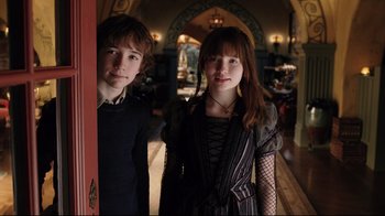 Movie still from “A Series of Unfortunate Events” (2004), directed by Brad Silberling – A couple of people standing next to each other in a room; Medium shot, Low angle