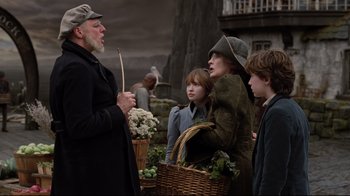 Movie still from “A Series of Unfortunate Events” (2004), directed by Brad Silberling – A group of people standing next to each other near a basket; Medium shot, Over the shoulder angle
