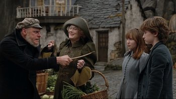 Movie still from “A Series of Unfortunate Events” (2004), directed by Brad Silberling – Two women and a man are standing in front of a basket of vegetables; Medium shot, Over the shoulder angle