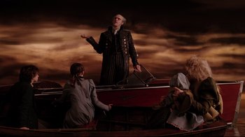 Movie still from “A Series of Unfortunate Events” (2004), directed by Brad Silberling – A man standing on top of a boat next to a group of people; Wide shot, Low angle
