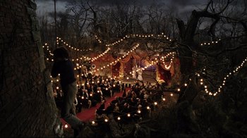 Movie still from “A Series of Unfortunate Events” (2004), directed by Brad Silberling – A crowd of people sitting in a forest at night; Extreme Wide shot, High angle