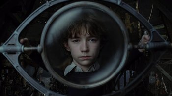 Movie still from “A Series of Unfortunate Events” (2004), directed by Brad Silberling – A young boy is looking into a round mirror; Close Up shot, High angle