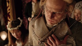 Movie still from “A Series of Unfortunate Events” (2004), directed by Brad Silberling – An old man with a long white beard is holding a necklace; Close Up shot, Low angle