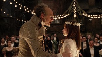 Movie still from “A Series of Unfortunate Events” (2004), directed by Brad Silberling – An older man and a young girl in a wedding scene; Medium shot, Over the shoulder angle