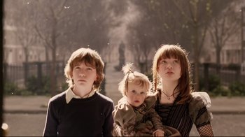 Movie still from “A Series of Unfortunate Events” (2004), directed by Brad Silberling – Three young children standing next to each other in front of trees; Medium shot, Low angle