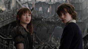 Movie still from “A Series of Unfortunate Events” (2004), directed by Brad Silberling – Two people standing next to each other in front of a building; Medium shot, Low angle