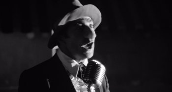 Movie still from “Lenny” (1974), directed by Bob Fosse – A black and white photo of a man singing into a microphone; Close Up shot, Low angle