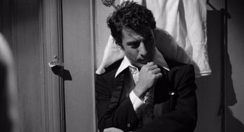 Movie still from “Lenny” (1974), directed by Bob Fosse – A man in a suit and tie leaning against a wall; Close Up shot, Low angle