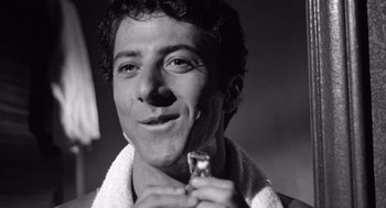 Movie still from “Lenny” (1974), directed by Bob Fosse – A black - and - white photo of a man holding a toothbrush; Close Up shot, Low angle