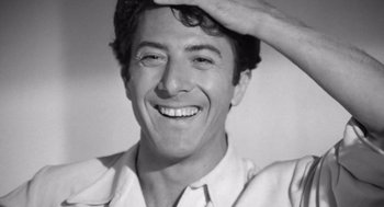 Movie still from “Lenny” (1974), directed by Bob Fosse – Black and white photograph of a man smiling for the camera; Close Up shot, Low angle