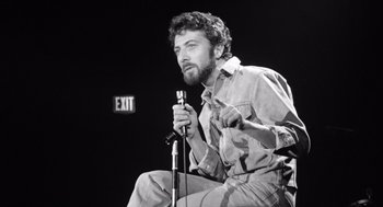 Movie still from “Lenny” (1974), directed by Bob Fosse – Black and white photograph of a man holding a microphone; Medium shot, Low angle