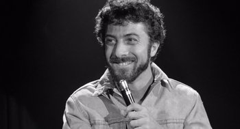 Movie still from “Lenny” (1974), directed by Bob Fosse – Black and white photograph of a man holding a microphone; Close Up shot, Low angle