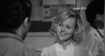 Movie still from “Lenny” (1974), directed by Bob Fosse – A young woman smiles at the camera while a young man looks on; Close Up shot, Over the shoulder angle