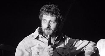 Movie still from “Lenny” (1974), directed by Bob Fosse – Black and white photograph of a man holding a pipe; Close Up shot, Low angle
