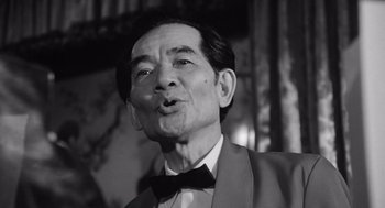 Movie still from “Lenny” (1974), directed by Bob Fosse – An older man wearing a suit and a bow tie; Close Up shot, Low angle