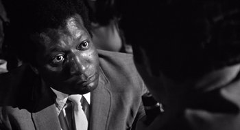 Movie still from “Lenny” (1974), directed by Bob Fosse – A black and white photo of a man in a suit and tie; Close Up shot, Over the shoulder angle