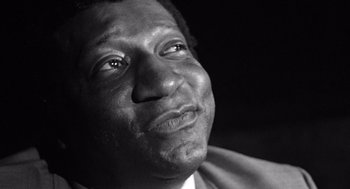 Movie still from “Lenny” (1974), directed by Bob Fosse – A black - and - white photo of a man looking up at the sky; Close Up shot, Low angle