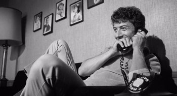 Movie still from “Lenny” (1974), directed by Bob Fosse – A man talking on a phone while sitting on a couch; Medium shot, Low angle