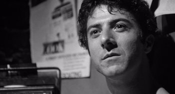 Movie still from “Lenny” (1974), directed by Bob Fosse – Black and white photograph of a young man looking into the camera; Close Up shot, Low angle