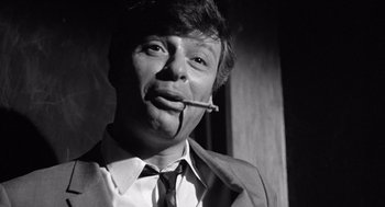 Movie still from “Lenny” (1974), directed by Bob Fosse – A black and white photo of a man smoking a cigarette; Close Up shot, Low angle