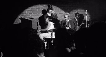 Movie still from “Lenny” (1974), directed by Bob Fosse – A group of people sitting around a stage; Wide shot, Low angle
