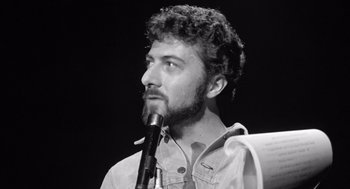 Movie still from “Lenny” (1974), directed by Bob Fosse – Black and white photograph of a man with curly hair and a beard; Close Up shot, Low angle