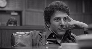 Movie still from “Lenny” (1974), directed by Bob Fosse – Black and white photograph of a man sitting at a table; Close Up shot, Low angle