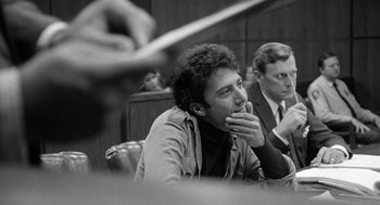 Movie still from “Lenny” (1974), directed by Bob Fosse – Two men are sitting in a courtroom and one of them is holding his hand to his mouth; Close Up shot, Over the shoulder angle