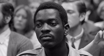 Movie still from “Lenny” (1974), directed by Bob Fosse – A black and white photo of a man in a crowd of people; Close Up shot, High angle