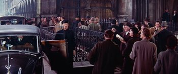 Movie still from “Les Girls” (1957), directed by George Cukor – A group of people standing around a building; Wide shot, High angle