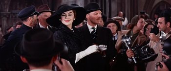 Movie still from “Les Girls” (1957), directed by George Cukor – A man and a woman wearing hats and holding a pipe; Medium shot, Low angle